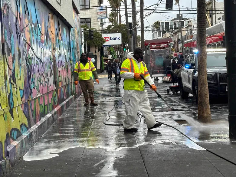 Two-person crew cleaning urban Bay Area sidewalk city street